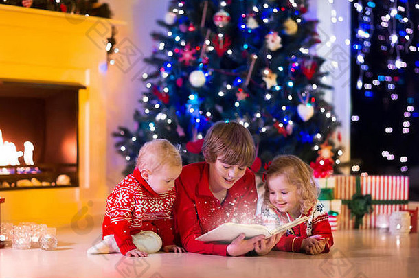 平安夜，孩子们在壁炉边看书，打开礼物。一家人带着孩子庆祝圣诞节。装饰客厅