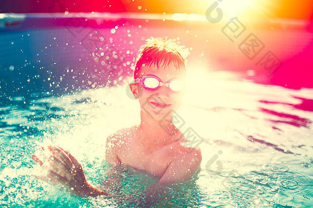 戴着护目镜的小孩在游泳池里溅水，夏日日落，复古