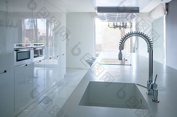 现代白色厨房透视图，带有集成的长凳水槽和弹簧水龙头