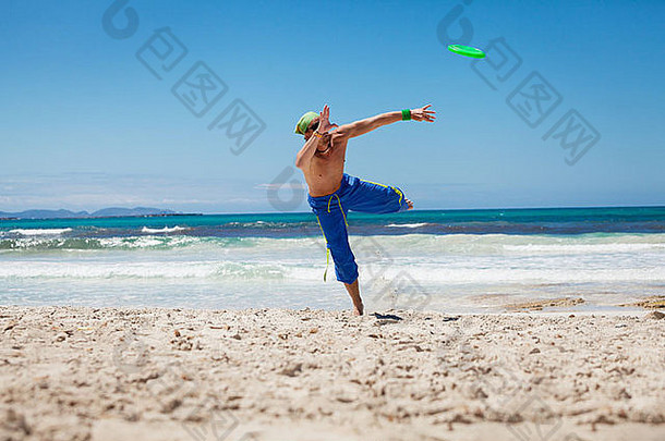 有吸引力的男人。玩弗里斯比海滩夏天体育运动健身跳