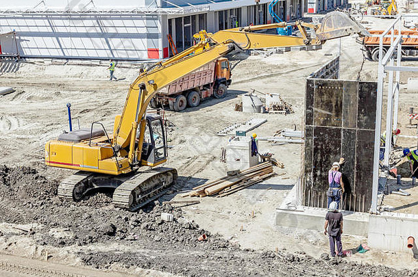 在工人们正在一个巨大的混凝土模具之前，查看建筑工地。