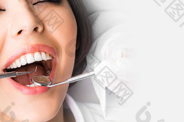 牙医检查患者牙齿，带有白色复印空间的特写视图