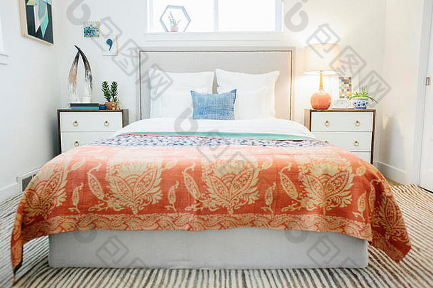 公寓中的卧室，有一张双人床，旁边有橱柜和一张图案鲜明的床罩