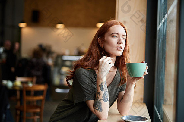 红色的头女孩手臂纹身坐着<strong>咖啡</strong>馆窗口利物浦