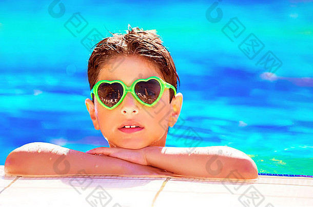 在豪华海滩度假酒店的泳池边，一个戴着墨镜的漂亮男孩在泳池边度过休闲时光的特写镜头