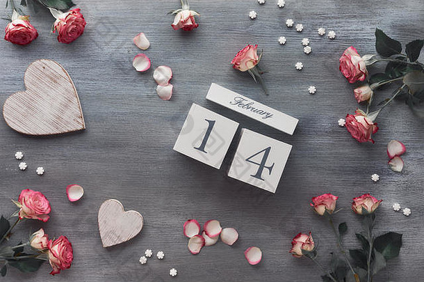 情人节庆典，平铺着木制日历，深灰色背景上有粉色玫瑰和木制心形图案