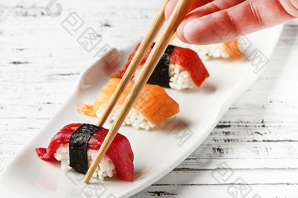 用筷子将三文鱼和<strong>红金鱼</strong>放在白色盘子上，放在古老的白色木头上。传统日本寿司风格的生鱼。水平图像。