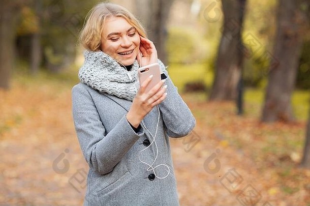 在秋天公园听音乐的年轻美女