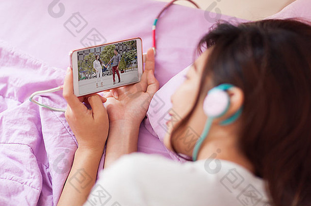 亚洲年轻女孩看手机视频智能手机戴耳机