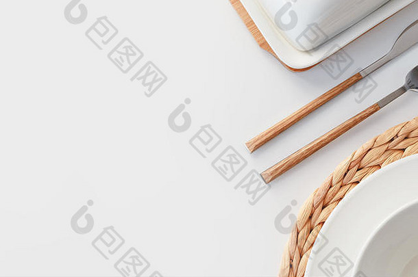白色陶瓷餐具、纤维编织圆形餐垫和餐具，背景为白色。斯堪的纳维亚风格。