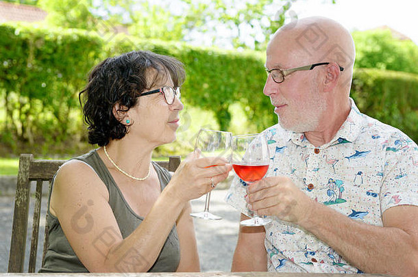 老夫妇在花园里喝着一杯葡萄酒