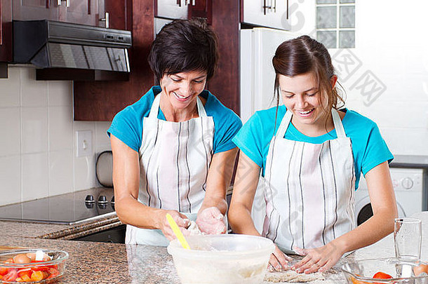 快乐的中年妈妈和十几岁的女儿在厨房烤面包