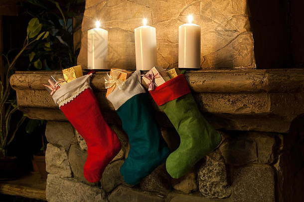 壁炉背景上的圣诞长袜。烟囱，蜡烛。圣诞袜、装饰品、礼物。