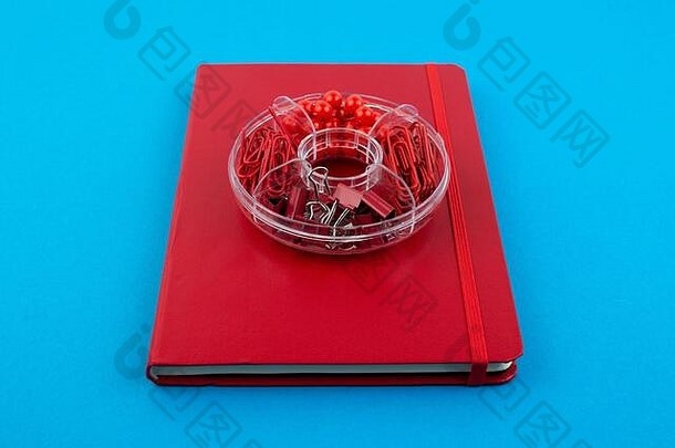 蓝色桌子上的红色商务笔记本和文具。回到学校或工作场所的抽象背景。最小成分。