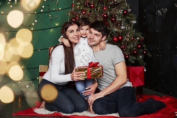 可爱的拥抱。冬夜，可爱的一家人坐在<strong>圣诞</strong>树旁，手里拿着礼品盒，享受着<strong>一起</strong>度<strong>过</strong>的时光
