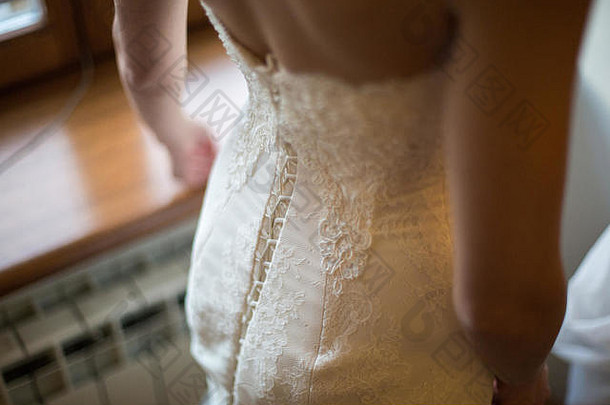 新娘从后面穿婚纱。