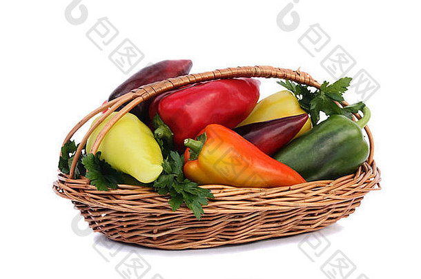 柳条篮子填满成熟的红色的黄色的绿色辣椒提出了白色背景