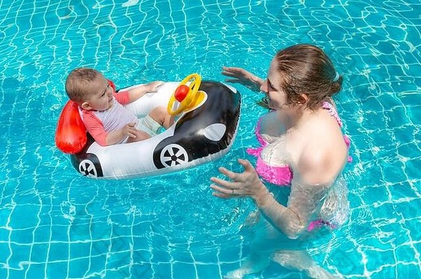 年轻快乐的妈妈穿着粉色比基尼，在游泳池里玩得很开心，还钓到了<strong>宝宝</strong>。一个快乐的小孩坐在汽车形状的充气船上。夏季海上休闲。