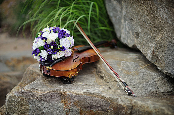 美丽的新娘花束和摇滚上的小提琴