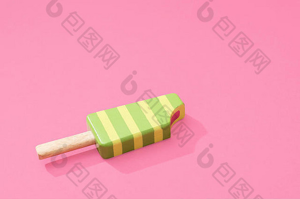 木制玩具条纹冰棒棒棒糖冰棒，在柔和的粉红色背景上有一点去掉，并留有和文本的空间