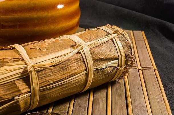 竹叶包装的中国普洱茶和竹垫上的茶具，特写