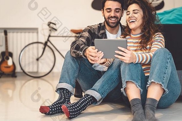 在家使用平板电脑的幸福夫妻——年轻社交人士享受新潮流科技设备带来的乐趣