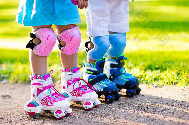 女孩男孩学习辊滑冰夏天公园孩子们穿保护垫安全头盔安全辊滑冰骑活跃的户外热点;