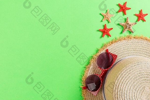 棕绿色桌子上有贝壳的沙滩帽。夏季背景概念，带空间俯视图。