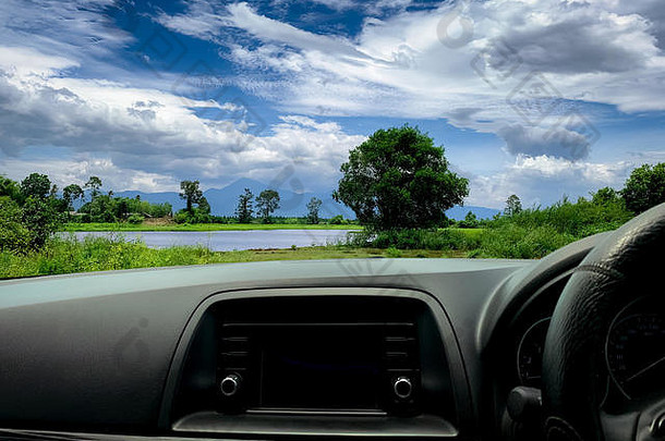 从车内可以看到美丽的风景。汽车内部的方向盘和仪表板。公路之旅，山、湖、林一览无余