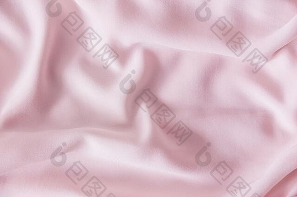 粉红色起皱的丝绸。粉红色的织物呈波浪状排列。粉色织物背景或纹理。