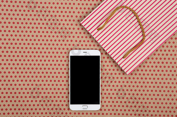 庆祝、商业和技术概念-手工条纹购物袋、礼品袋和白色智能手机，背景为红色波尔卡d