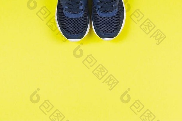 黄色背景的经典蓝色运动鞋。健康生活方式和日常训练的理念。放置文本。