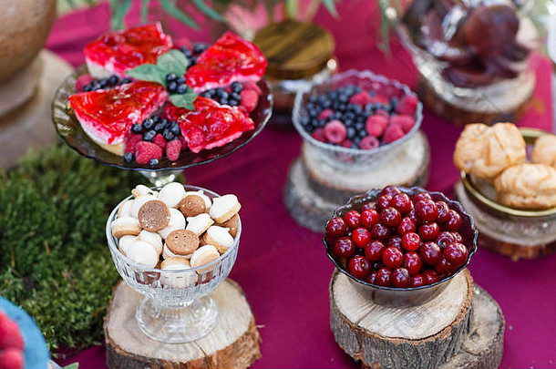 在森林里举行婚礼。桌上有浆果、蓝莓和覆盆子的蛋糕。Fourchette，桌上有很多食物