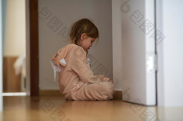 心烦意乱的女孩坐在门边的地板上