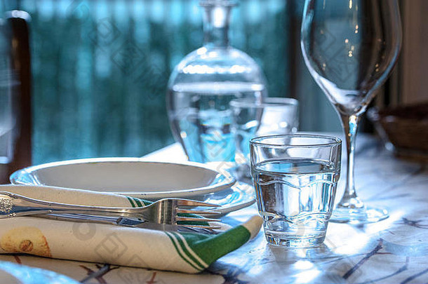 优雅的餐桌，可在夏季用餐，配有白色瓷盘、白色复古花边餐巾和玻璃器皿