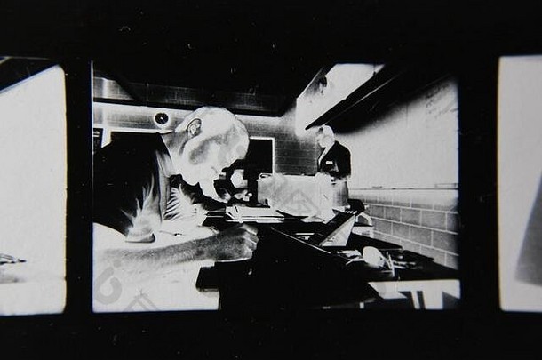 精美的70年代复古隐形打印黑白极端照片，一名学生在教室里做手写笔记。