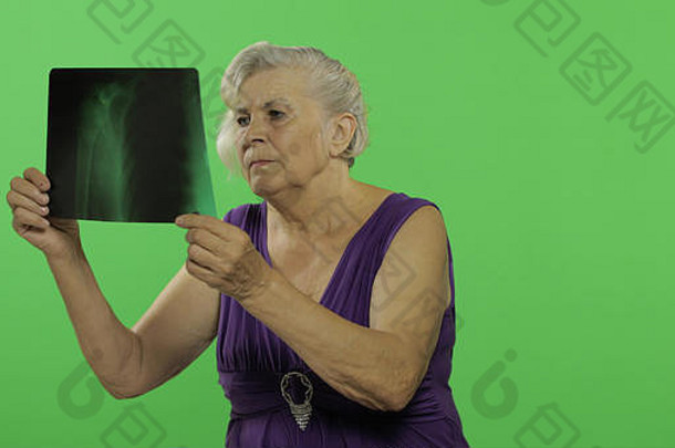 一位上了年纪的妇女正在检查她的x光照片。穿着紫色连衣裙的漂亮老奶奶。放置您的徽标或文字。色度键。绿色屏幕背景