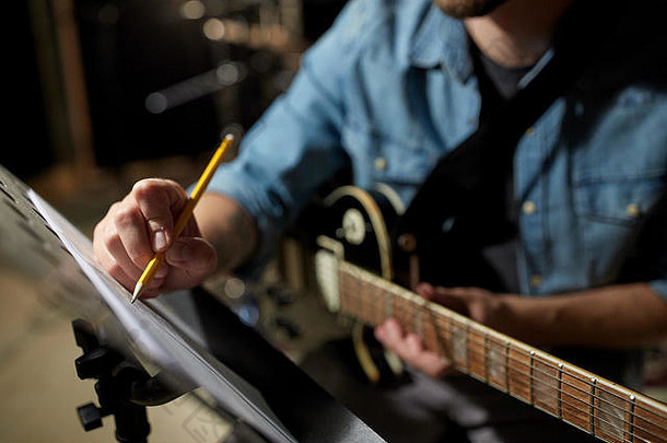 一个拿着吉他的男人在录音室给音乐书写东西