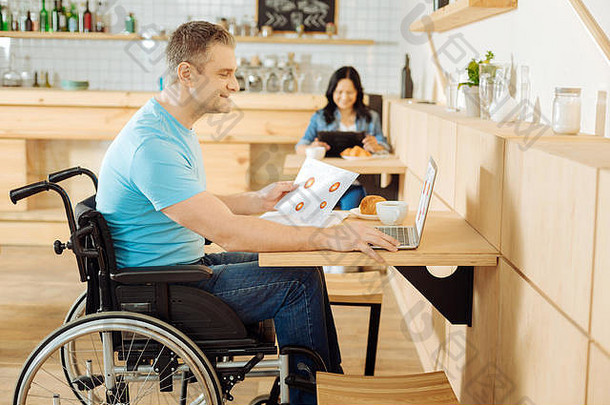 微笑的残疾人在他的笔记本电脑上工作