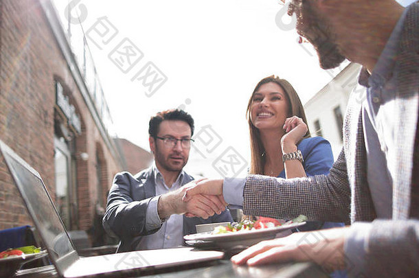 在街头咖啡馆的桌子上与同事握手