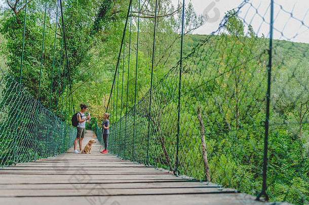 母女俩和小黄<strong>狗</strong>在森林里走过木制吊桥