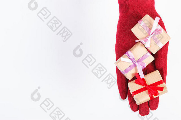 圣诞、情人节、<strong>生日</strong>或其他庆祝活动中戴红色羊毛手套和包装好的礼物的女士的手，白色背景，