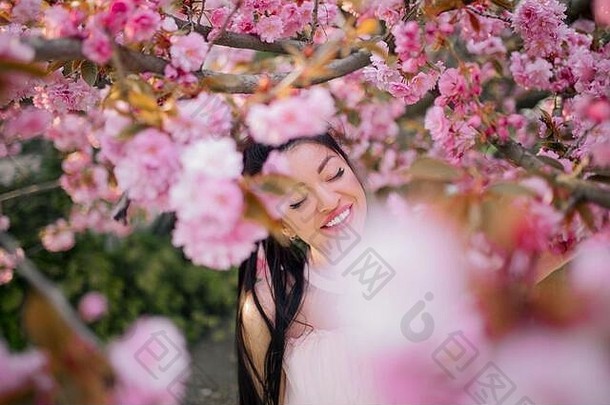 年轻的女人白色衣服享受放松公园盛开的樱花树肖像