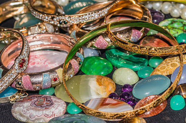 一堆珠宝、金手镯、珍珠项链和彩色宝石。财富与投资背景
