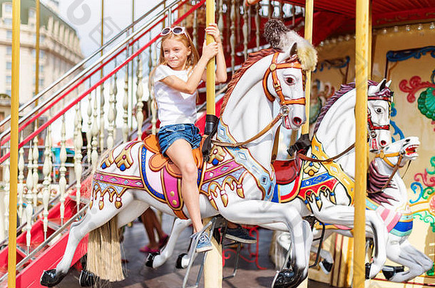 骑旋转木马的女孩。小女孩玩旋转木马，夏日快乐，快乐童年和假期概念