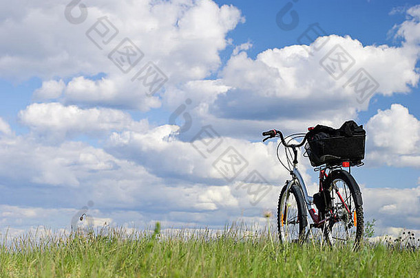 骑自行车旅行。在草地上骑自行车顶住云层
