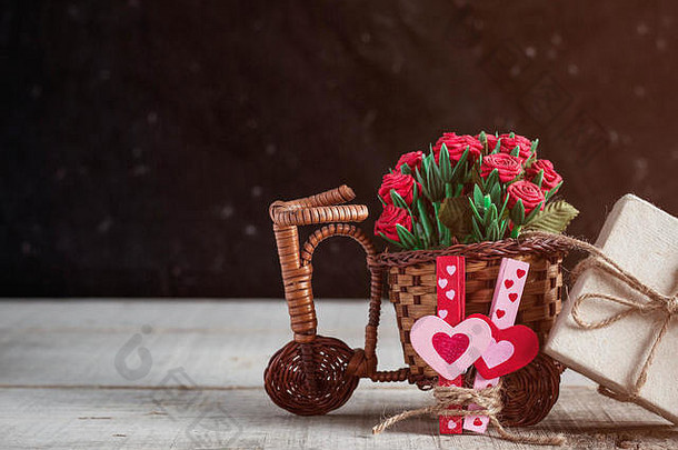 旧木地板上放着一束玫瑰和礼物的自行车。