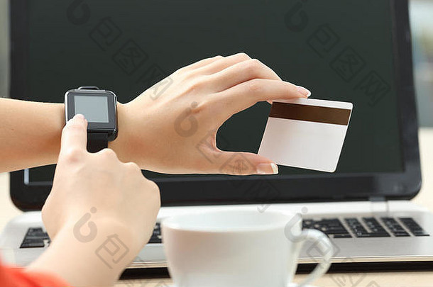 一位女士手持智能手表和在网上购物，背景是笔记本电脑