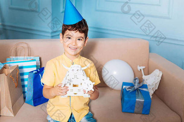 戴派对帽的快乐小男孩与玩具机器人合影