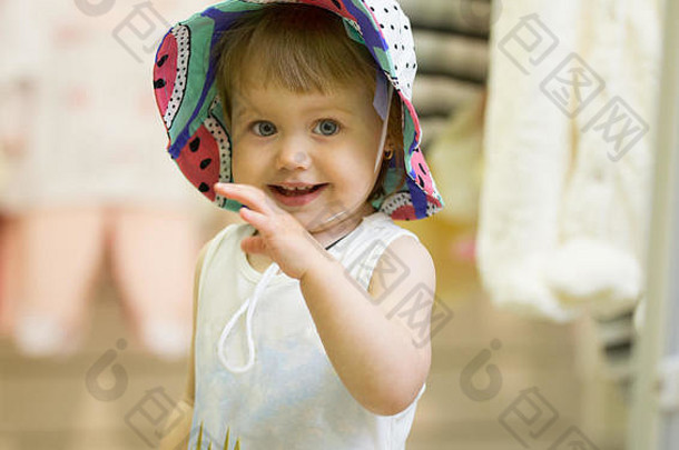 可爱女孩在儿童商店试戴彩色帽子